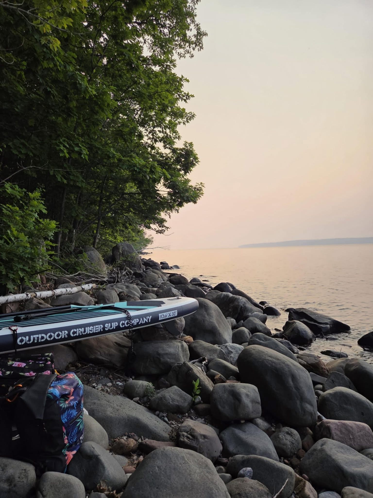 Loaded paddleboards resting on a rocky Lake Superior shoreline